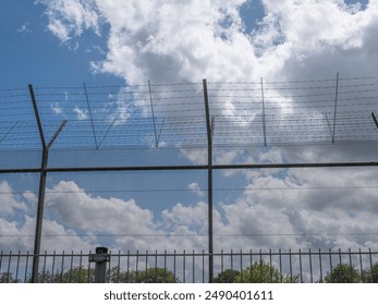 Barbed wire fence against blue sky with white clouds
 - Powered by Shutterstock