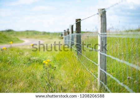 A barbed wire fence by a golf course, farmland to protect and keep live stock safe