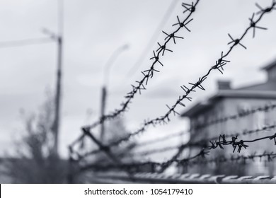 barbed wire fence enclosing the prison and places of detention for prisoners punished for committing criminal offences - Shutterstock ID 1054179410