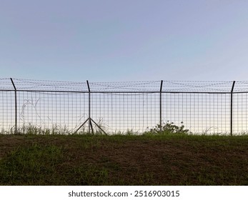 Barbed wire fence with grass and clear blue sky - Powered by Shutterstock