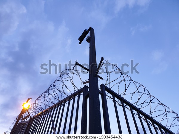 Barbed\
wire fence and lighting at night. Security\
fence.