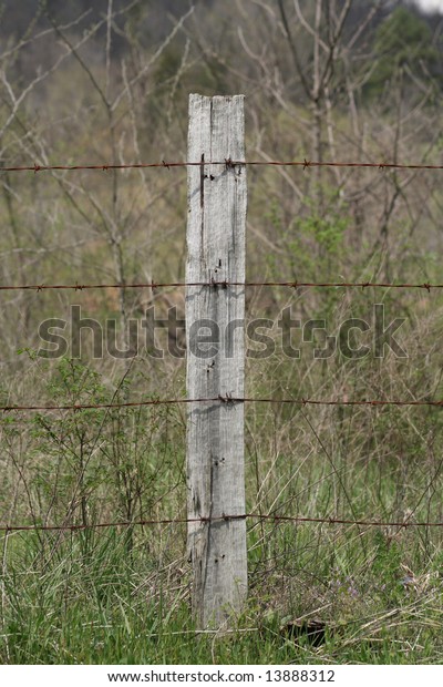 A barbed wire fence on a\
post