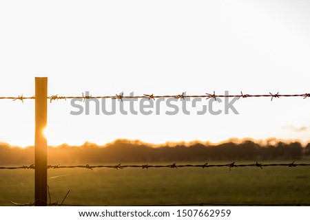 a barbed wire fence at sunset