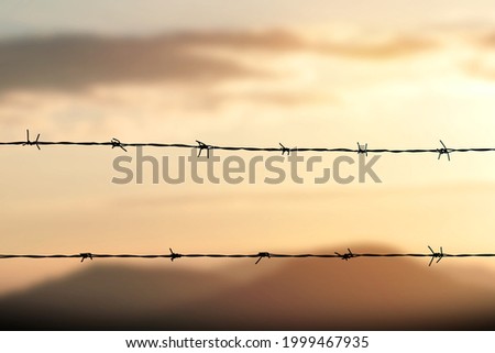 Barbed wire fence with Twilight sky to feel Silent and lonely and want freedom.