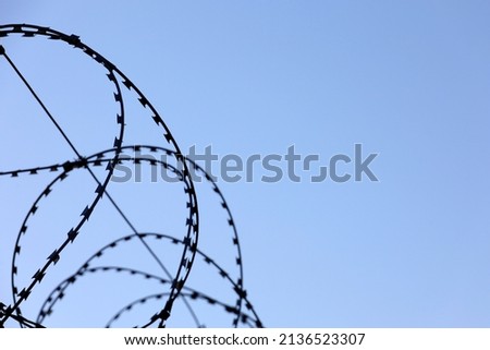 Barbed wire on blue sky background. Concept of boundary, prison, war or military base