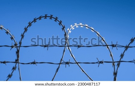 Barbed wire protection fence. Concept photo for security and lack of freedom. Blue sky background.
