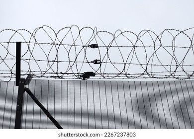 Barbed wire and specially made razor-sharp razor blades mounted on a high fence construction to stop immigrants or those with bad intentions from climbing over fences - Shutterstock ID 2267237803