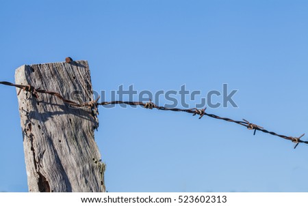 Barbed wireÂ tack and wooden post  blue background