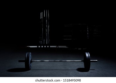 Barbell On Gym Floor. Weigh Lifting. Bench Press. Light From Above, Dark Background.