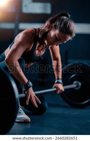 Barbell prep with added weights involves a woman, readying for training to boost strength in a gym