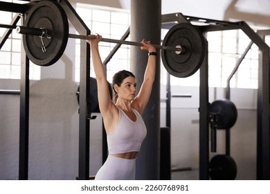 Barbell press, woman and exercise for fitness, workout and sports training in gym. Athlete, bodybuilder and overhead weightlifting for wellness, power and energy with motivation, performance or focus - Powered by Shutterstock