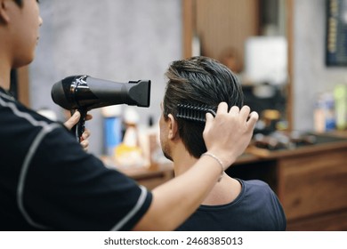 Barber blow drying hair of client after haircut - Powered by Shutterstock