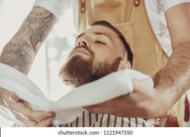 Barber covers the face of a man with a beard with a hot towel. Photo in vintage style - Powered by Shutterstock