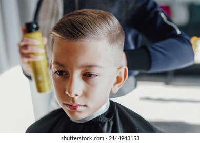 Barber cuts a boy's hair, cute boy sits in a barbershop for a haircut, fashion haircut for a guy