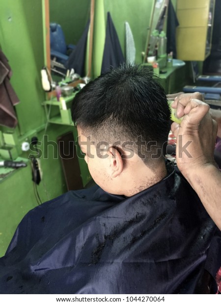 Barber cutting\
teenager hair with clipper.Man\'s grooming trimmer in a beauty\
salon.Hair dressing\
concept.