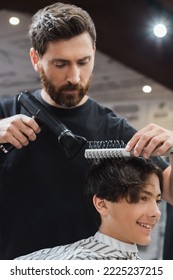 Barber Drying And Combing Hair Of Smiling Teen Boy In Beauty Salon