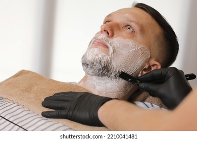 Barber Man Is Shaving Client With A Vintage Straight Razor In A Barbershop. Shaving Cream, Foam. Classic Shave By Stainless Steel Straight Edge Razor