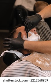 Barber Man Is Shaving Client With A Vintage Straight Razor In A Barbershop. Shaving Cream, Foam. Classic Shave By Stainless Steel Straight Edge Razor