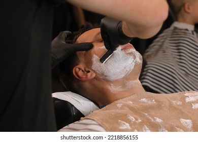 Barber Man Is Shaving Client With A Vintage Straight Razor In A Barbershop. Shaving Cream, Foam. Classic Shave By Stainless Steel Straight Edge Razor