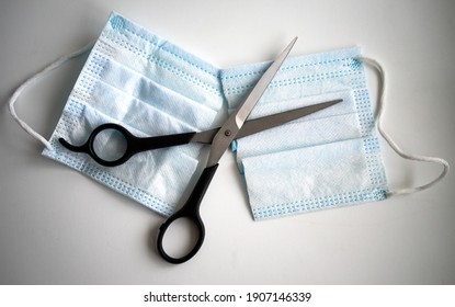 Barber scissors cut the medical mask in two halves, end of restrictions. - Powered by Shutterstock