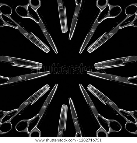 Barber scissors in the shape of a circle on a black background. A conceptual shot of a hairdresser's scissors.