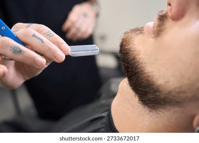 Barber sharpens beard edges using precision blade