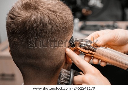 Similar – Image, Stock Photo Barber shaves the temple with cordless trimmer during a short haircut on the sides of the head.