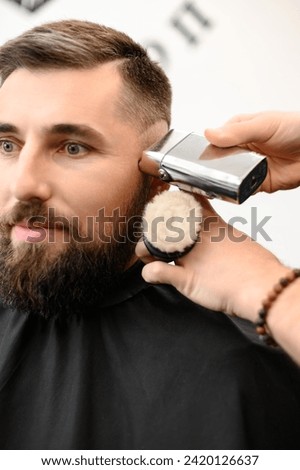 Similar – Image, Stock Photo Barber shaves the temple with cordless trimmer during a short haircut on the sides of the head.