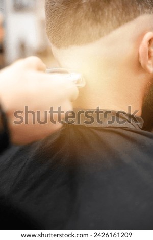 Similar – Image, Stock Photo Barber shaves the temple with cordless trimmer during a short haircut on the sides of the head.