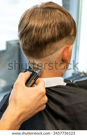 Similar – Image, Stock Photo Barber shaves the temple with cordless trimmer during a short haircut on the sides of the head.