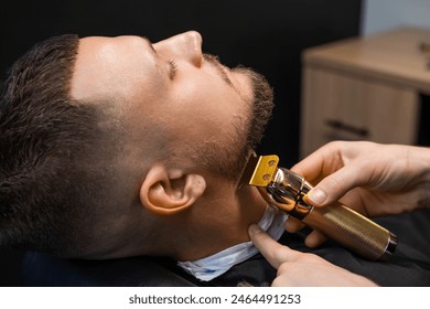 Barber shearing beard to man in barbershop, close up. - Powered by Shutterstock