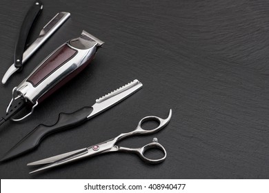 Barber shop equipment on Black background with place for text.  Professional hairdressing tools. Comb, scissor, clippers and hair trimmer isolated. 