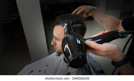 Barber shop. Man in barber's chair, hairdresser styling his hair