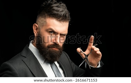 Barber styles modern beard with sharp scissor. Scissor snips through thick beard at barber shop. Beard transformation by expert barber using scissor. Vintage barber with silver scissor trimming beard.