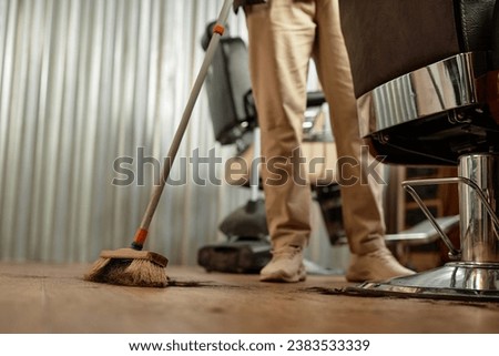 Barber sweeping after customer in hair salon