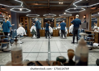 Barber team at work. Several professional barbers working with clients in the modern loft style barber shop. General view. Hairdresser services. Beauty salon. Barbershop interior