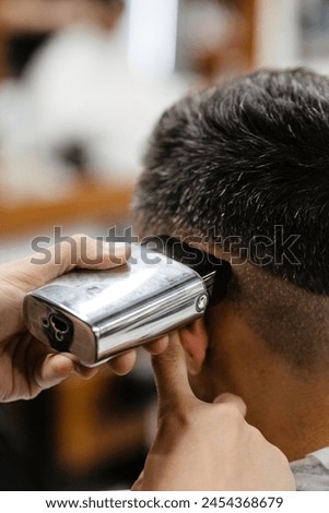 Similar – Image, Stock Photo Barber shaves the temple with cordless trimmer during a short haircut on the sides of the head.