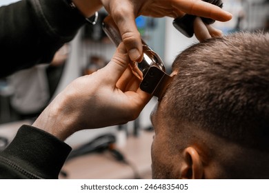 Barber uses an electrical trimmer to shave the clients hair in the sleek, contemporary barbershop - Powered by Shutterstock