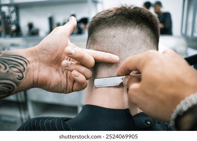 Barber using folding shaving razor on neck of client in barbershop 