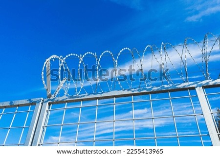 Barbered wire over a blue sky and on building ground, rusty