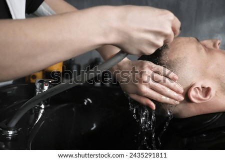 Barbershop. Hairstylist washing client hair in barber shop
