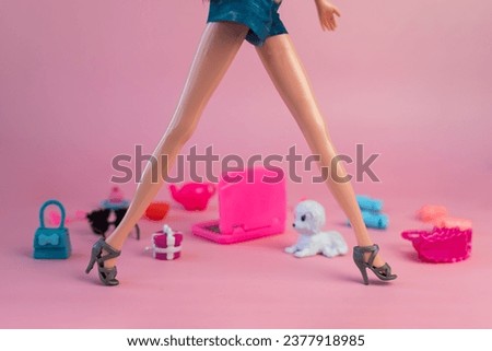 Barbie doll in a pink dress on a pink background. various accessories for playing with a doll.
