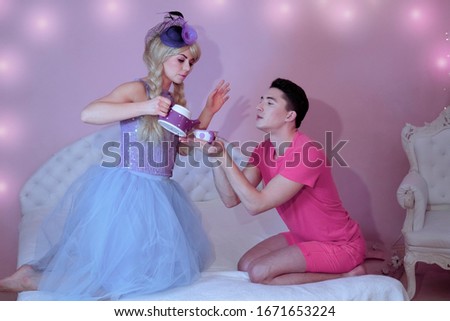 Barbie doll wants to feed Ken a beautiful cake with colored cream. People dressed in toy costumes for a fun party.