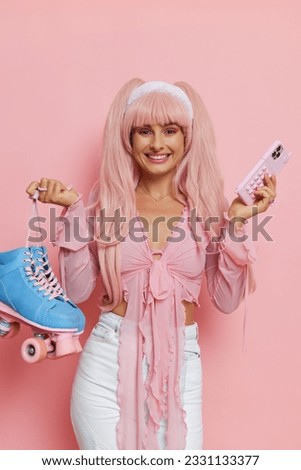 Barbie style girl wearing pink shirt and pink wig with long hair, posing with smile on pink backdrop, holding phone and roller-skates, vintage fashion concept, copy space