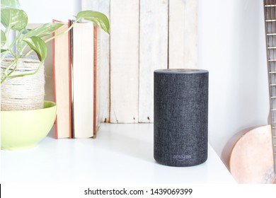 BARCELONA, JULY 1, 2019: Alexa Echo smart loudspeaker next a Spanish guitar and some books in a livingroom.
