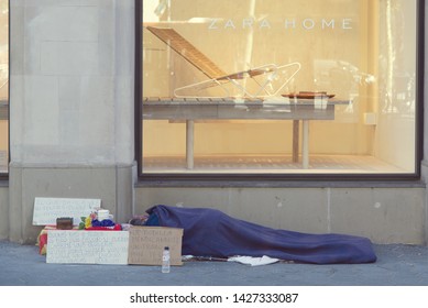 BARCELONA, JUNE 18, 2019: Homeless person sleeping in the street in front of a Zara Home shop window in Paseig de Gracia, Barcelona