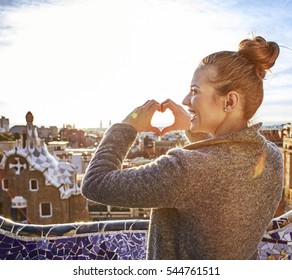 Barcelona Signature Style. Seen From Behind Young Tourist Woman In Coat In Barcelona, Spain Showing Heart Shaped Hands