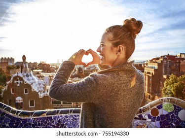 Barcelona Signature Style. Seen From Behind Young Tourist Woman In Coat In Barcelona, Spain Showing Heart Shaped Hands