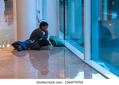 Barcelona / Spain 02 20 2019: African Boy Sitting On The Floor In Airport And Looks Out The Window At Planes. Child Is Bored Waiting For Departure.