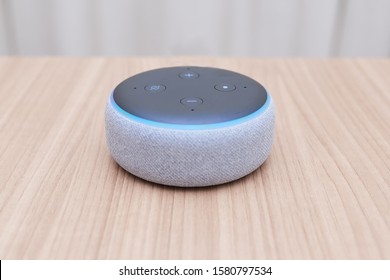 Barcelona, Spain - 03 of december of 2019: third generation amazon echo dot, white, low view, with blue light on, on a light wooden table